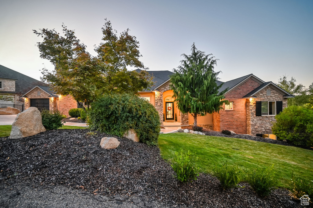 View of front of house with stone siding, a front yard, and a garage