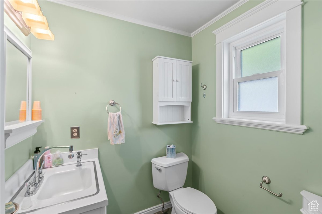 Bathroom featuring toilet, ornamental molding, baseboards, and vanity