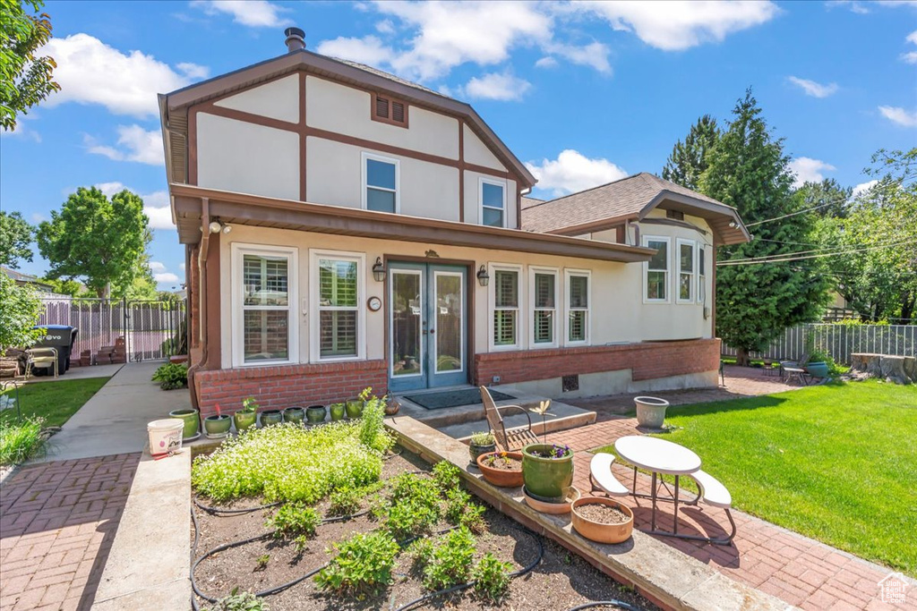 View of front facade featuring french doors, a patio, brick siding, and stucco siding