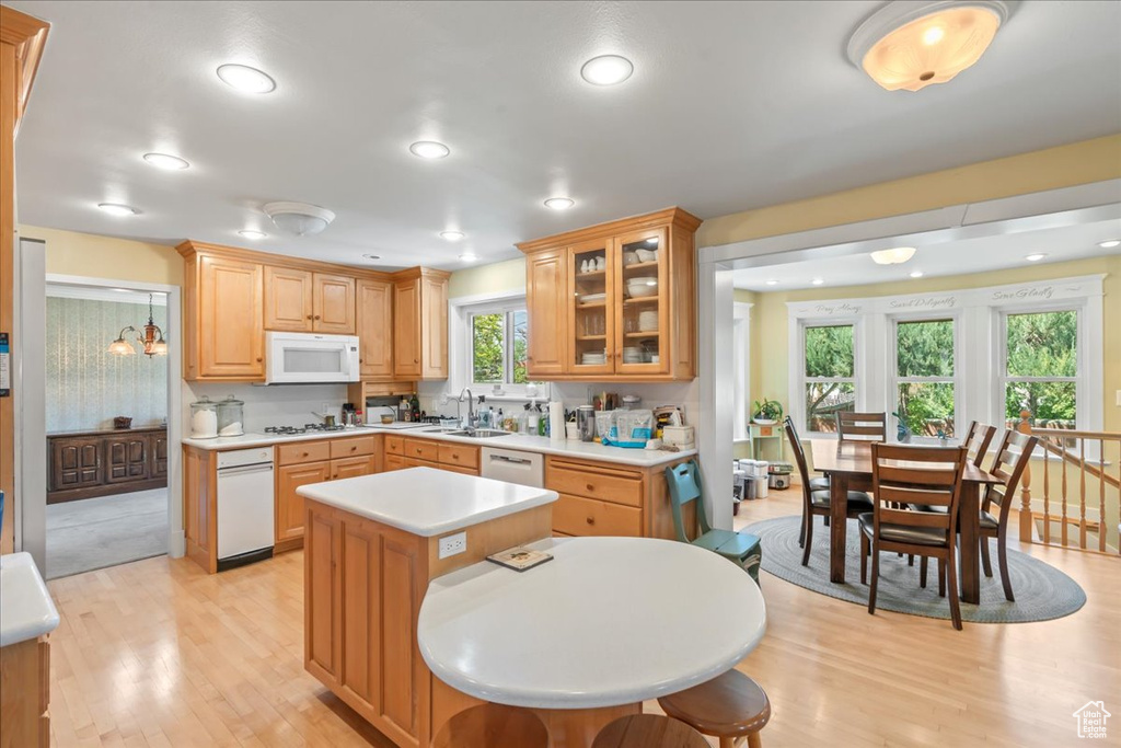 Kitchen with white appliances, light countertops, light wood-style floors, a sink, and glass insert cabinets
