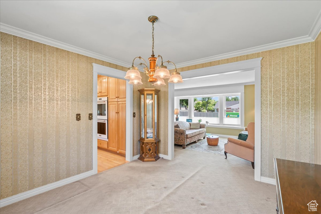 Dining area featuring wallpapered walls, light carpet, a chandelier, baseboards, and ornamental molding