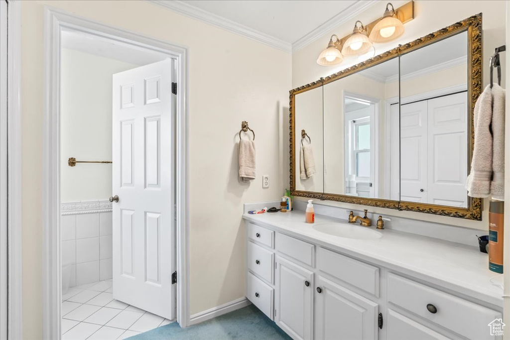Bathroom with ornamental molding, vanity, tile patterned flooring, and baseboards