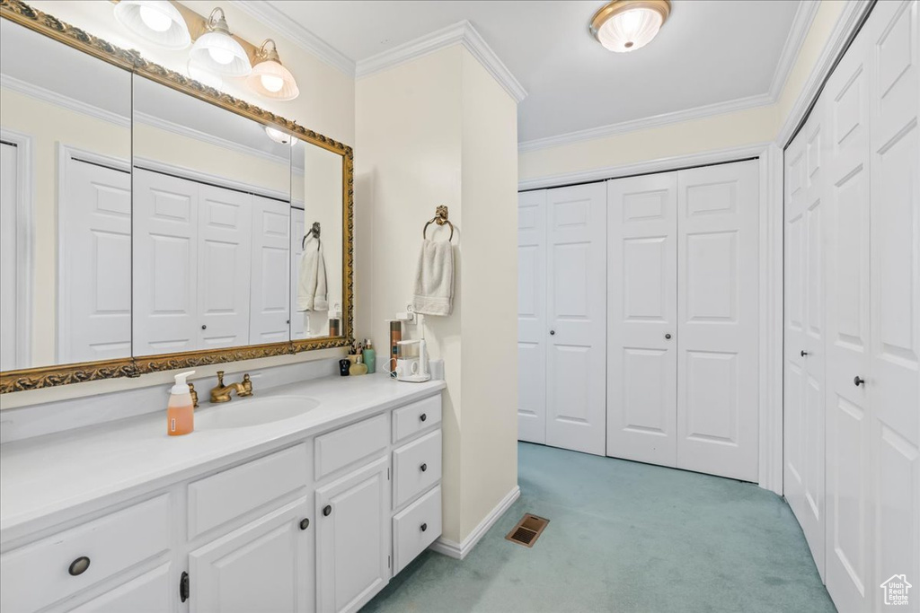 Bathroom featuring a closet, crown molding, vanity, and baseboards