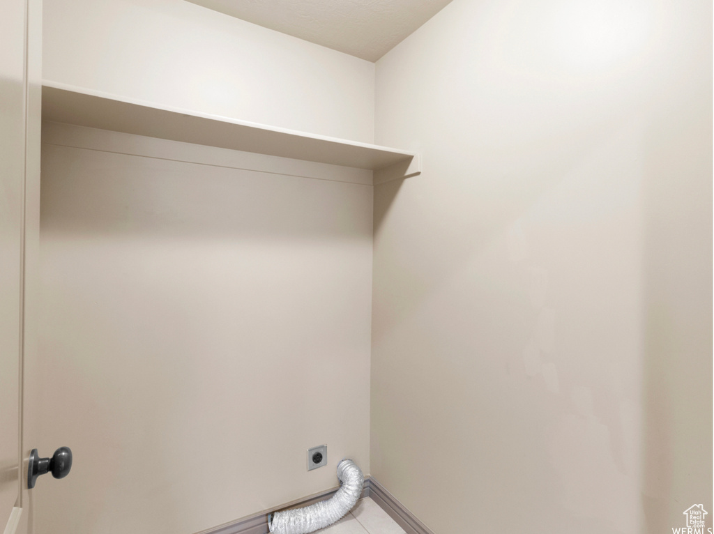 Washroom with laundry area, light tile patterned floors, baseboards, and hookup for an electric dryer