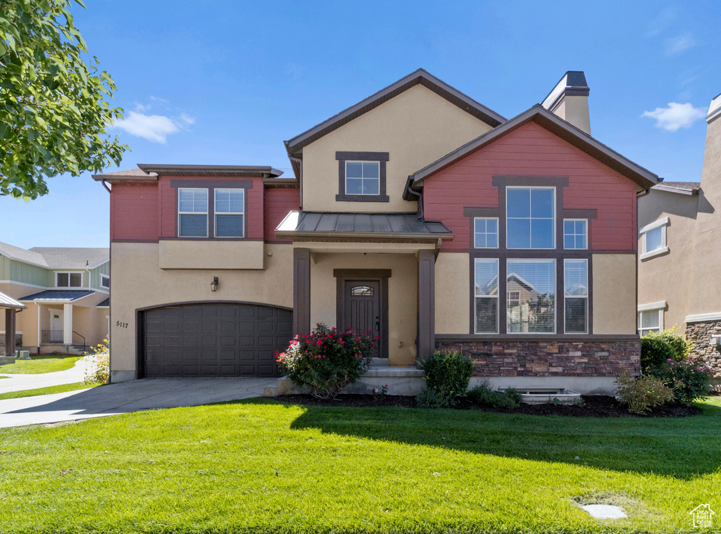 View of front of home featuring stone siding, concrete driveway, a garage, stucco siding, and a front lawn
