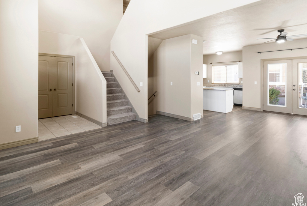 Unfurnished living room featuring french doors, wood finished floors, stairway, a ceiling fan, and baseboards