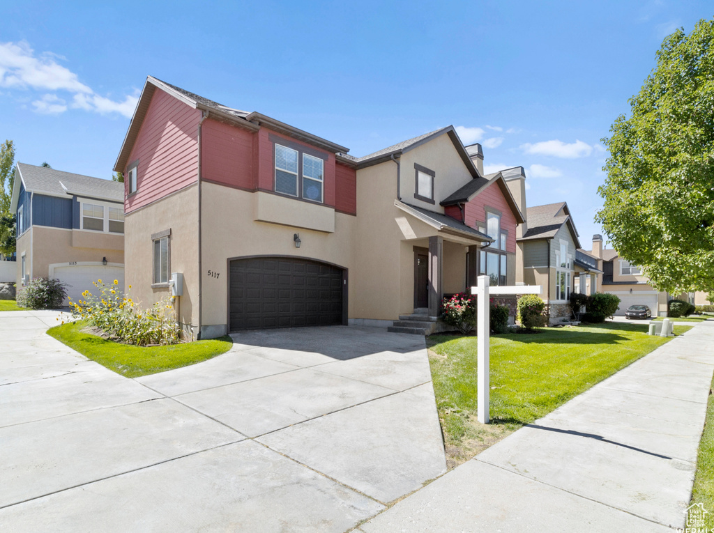 View of front of home featuring driveway, an attached garage, stucco siding, a residential view, and a front lawn
