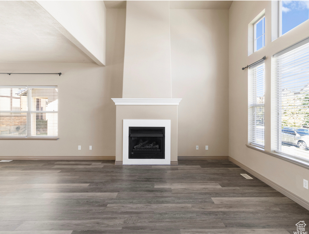 Unfurnished living room with a healthy amount of sunlight, a fireplace, and wood finished floors