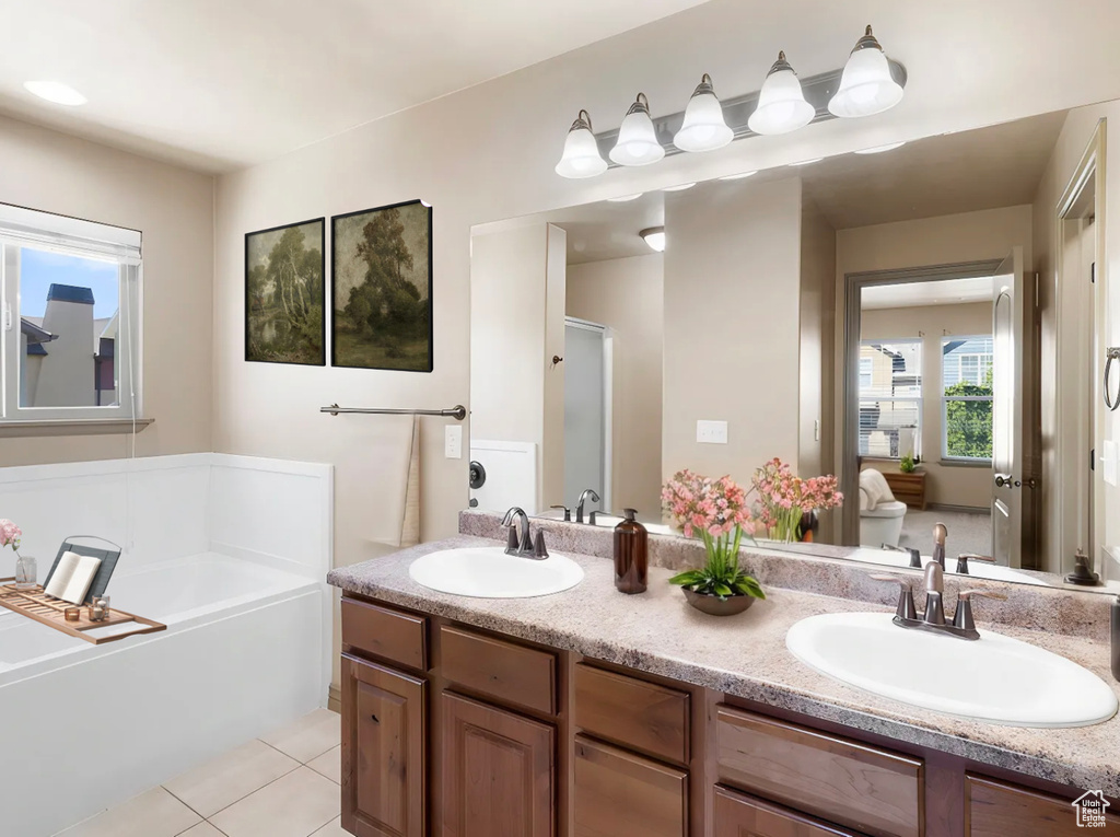 Full bath featuring a bath, tile patterned flooring, double vanity, and a sink