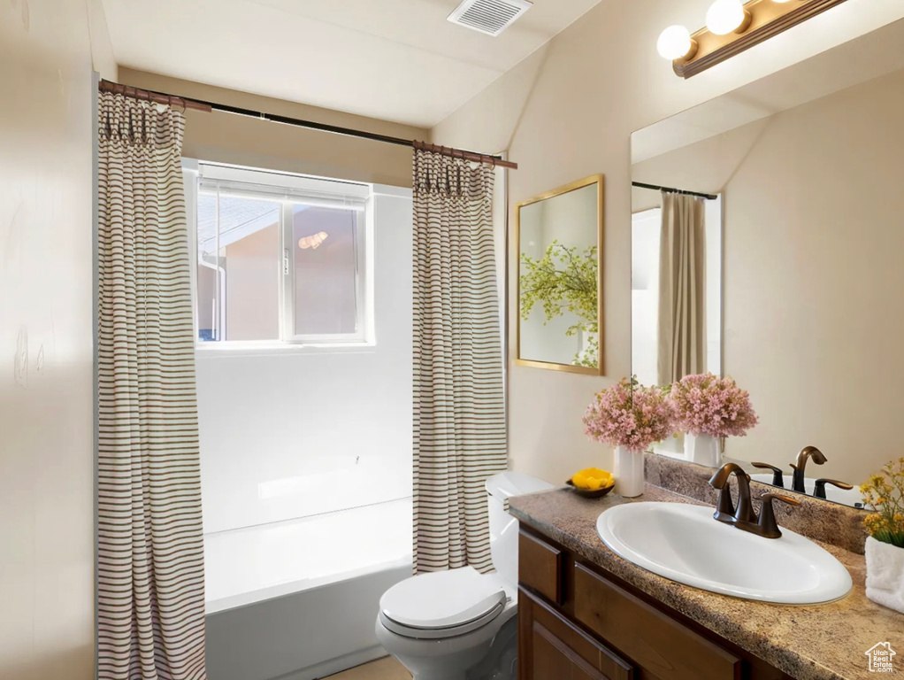 Full bathroom with vanity, toilet, shower / bath combo with shower curtain, and visible vents