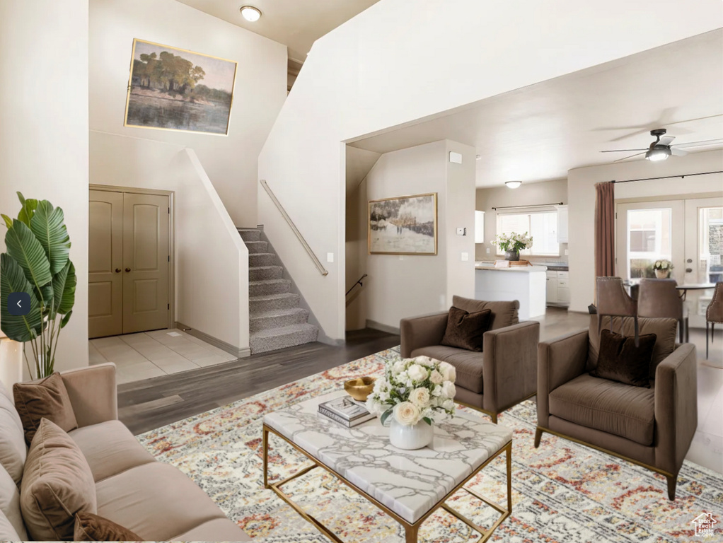 Living room featuring stairway, light wood-style flooring, baseboards, and ceiling fan