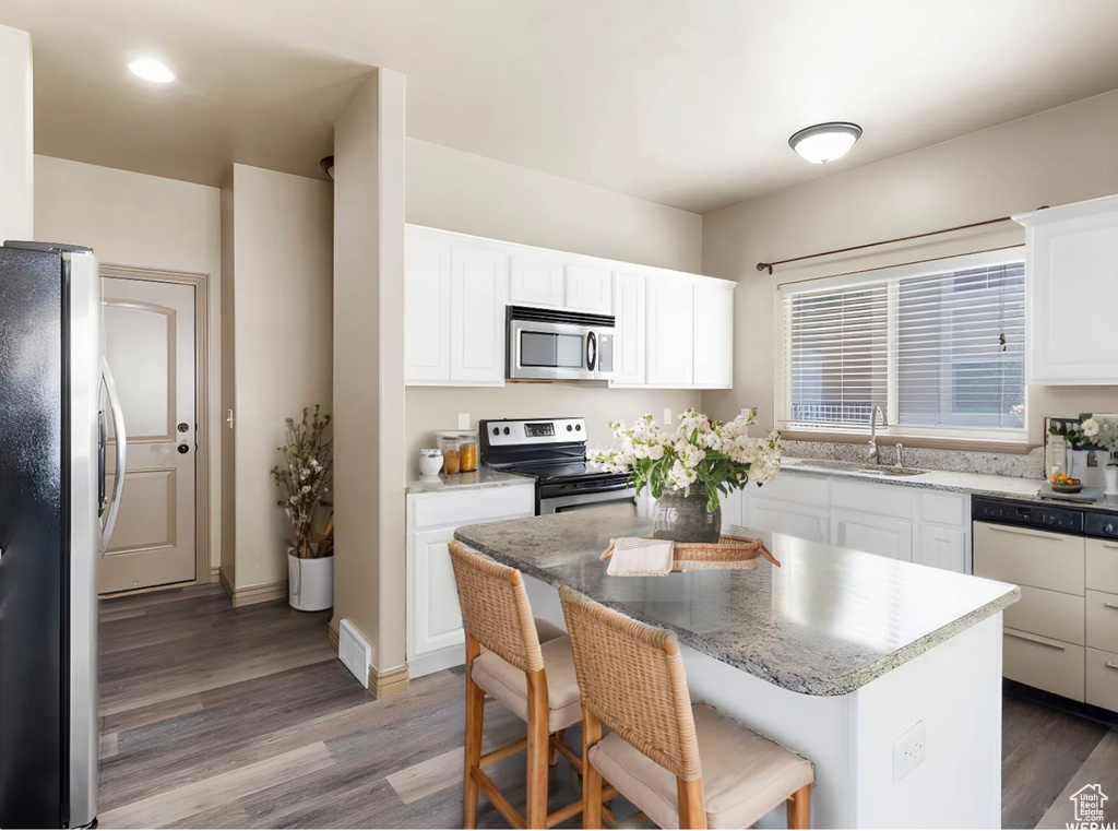 Kitchen with a center island, light wood-type flooring, stainless steel appliances, and a sink