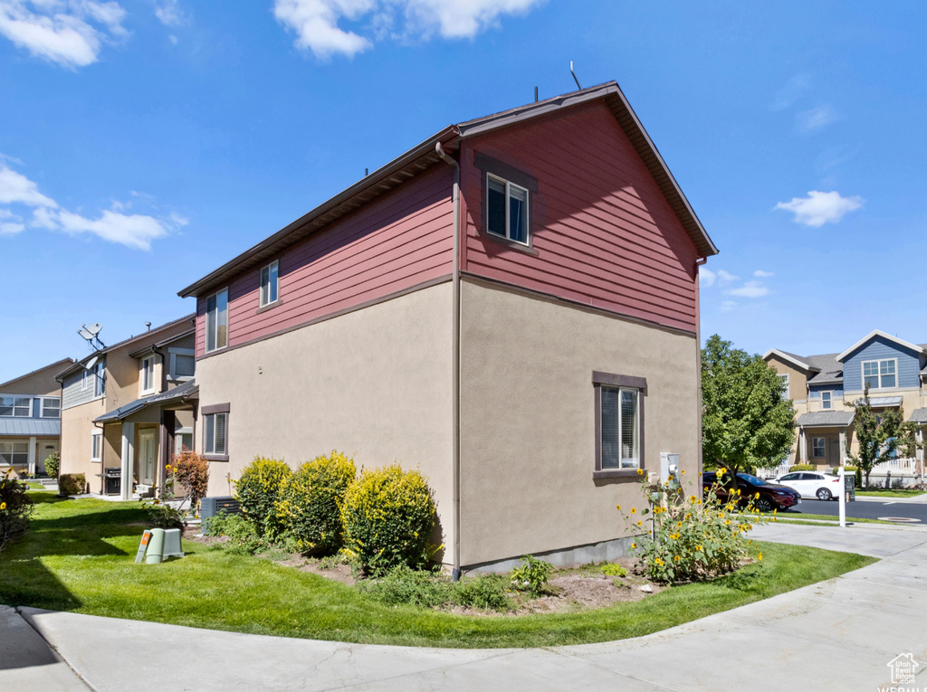 View of side of home with a yard, stucco siding, and a residential view
