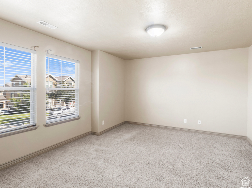 Spare room featuring light carpet, baseboards, and visible vents