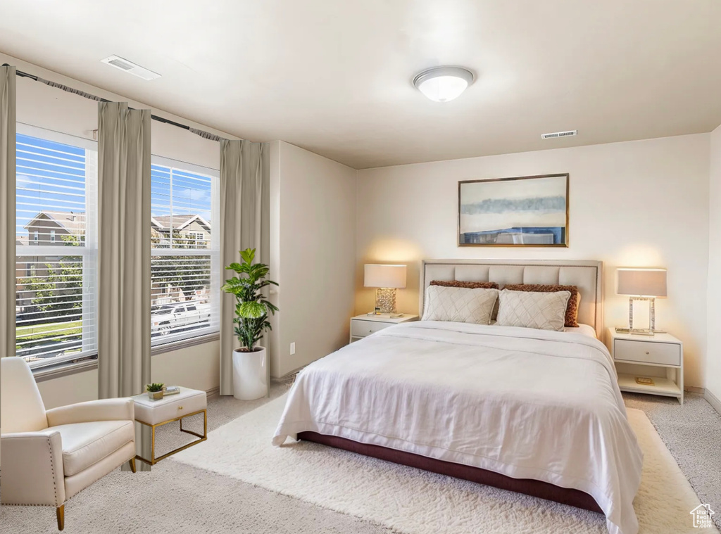 Bedroom with baseboards, visible vents, and light colored carpet