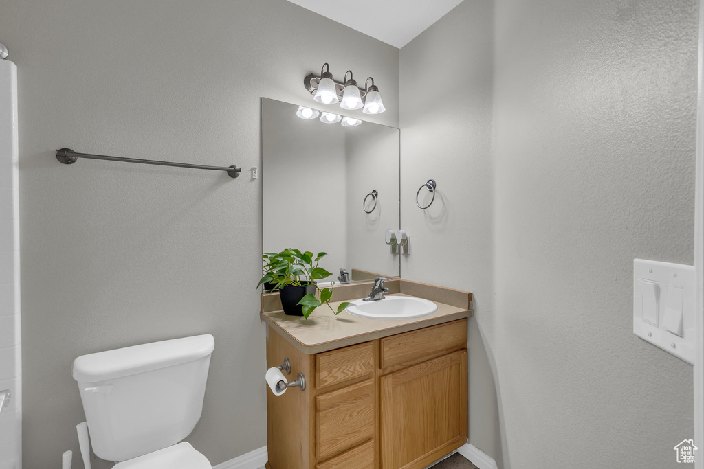 Bathroom featuring toilet, vanity, and baseboards