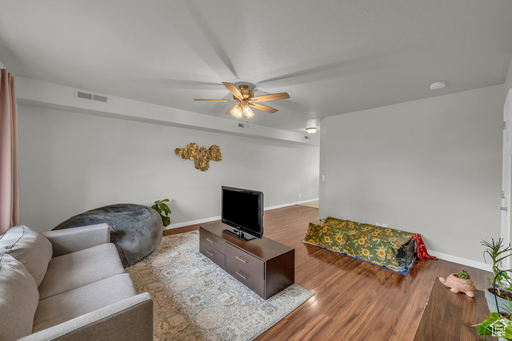 Living area with ceiling fan, wood finished floors, and baseboards