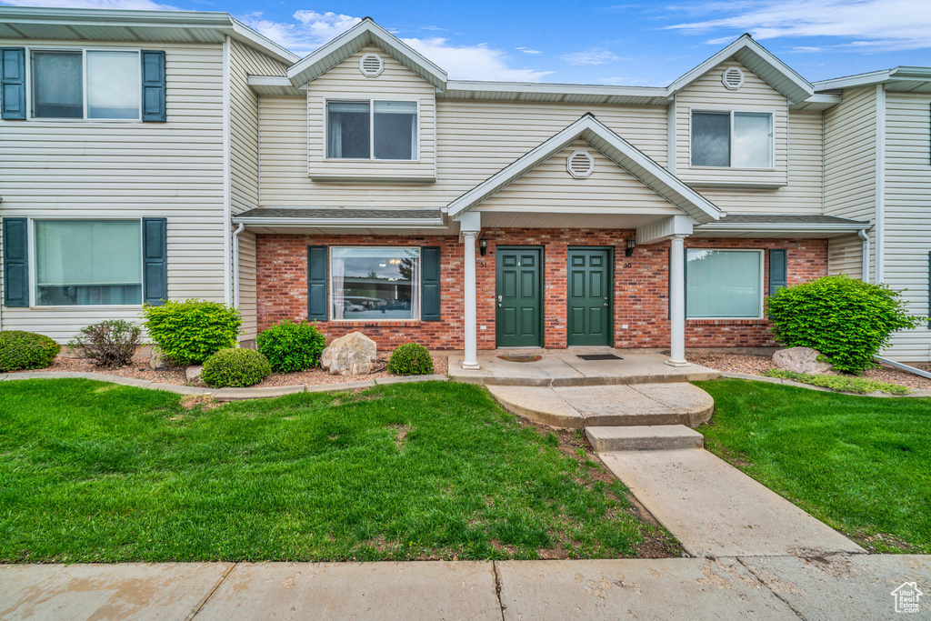 Multi unit property featuring brick siding and a front lawn
