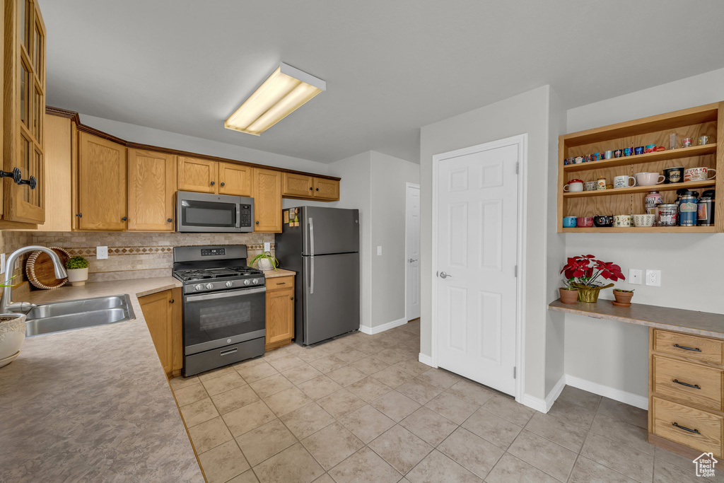 Kitchen with appliances with stainless steel finishes, a sink, backsplash, light countertops, and open shelves