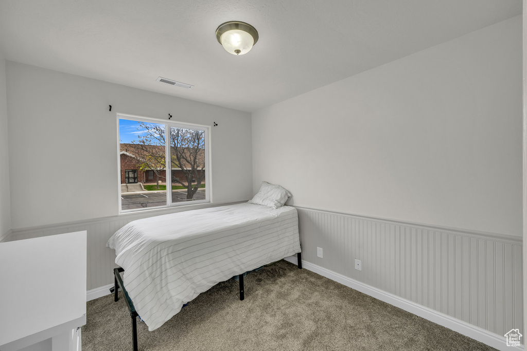 Bedroom with a wainscoted wall and carpet flooring