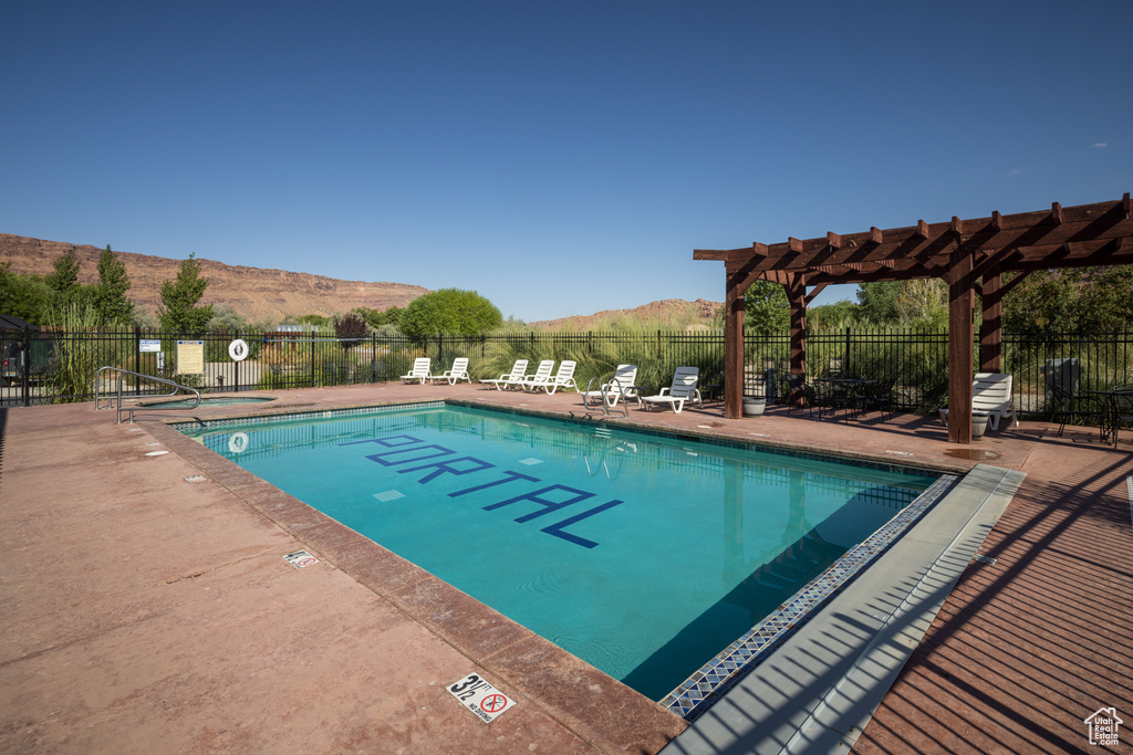 Community pool with fence, a mountain view, a pergola, and a patio area
