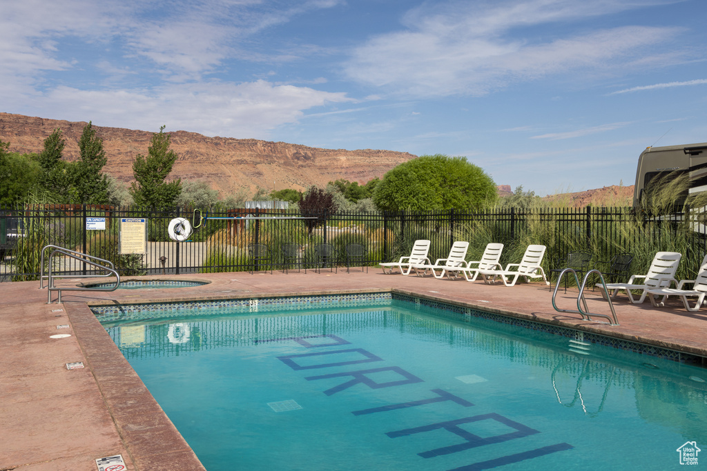 Community pool featuring a community hot tub, fence, a patio, and a mountain view