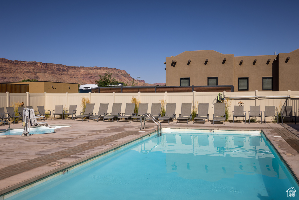 Community pool with a mountain view, fence, and a patio