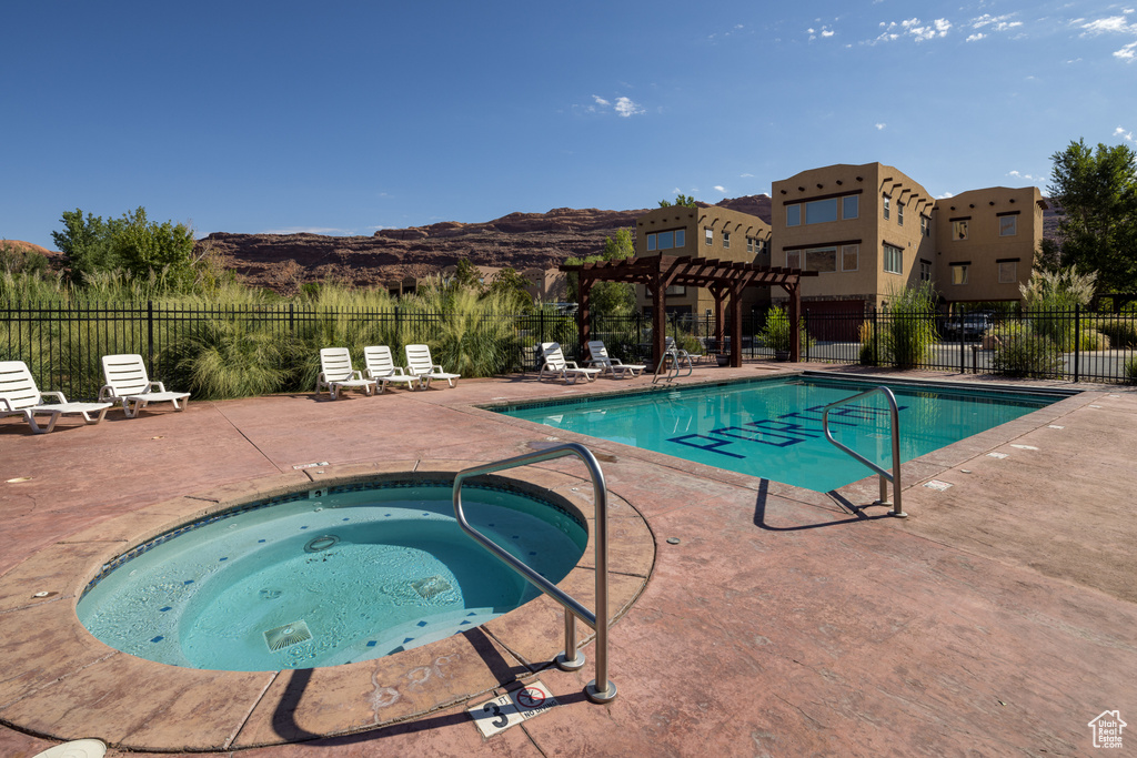 Community pool with a pergola, a community hot tub, a patio area, fence, and a mountain view