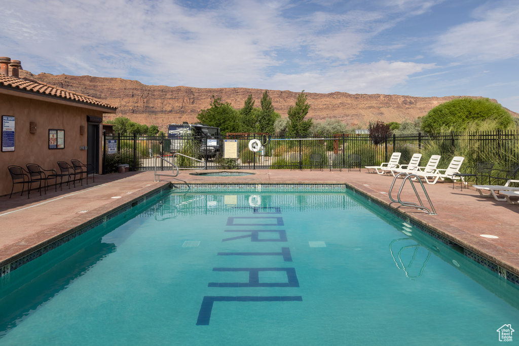 Community pool featuring a mountain view, a community hot tub, and fence