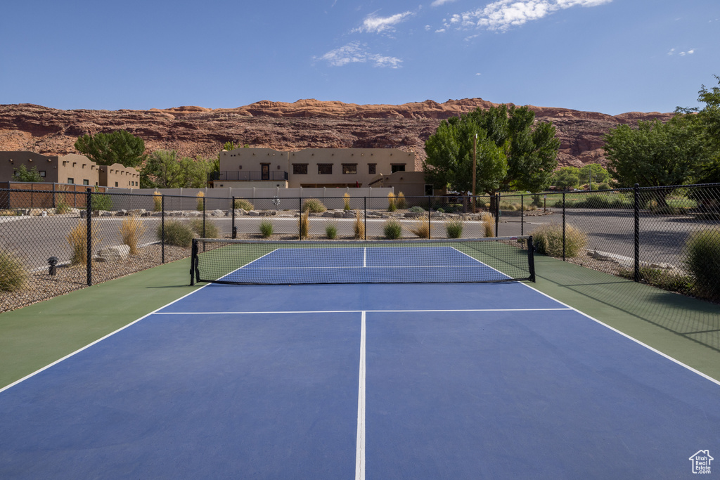 View of tennis court with a mountain view, fence, and community basketball court