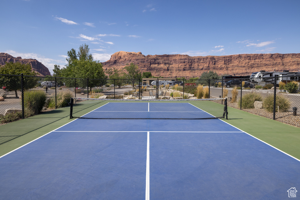 View of tennis court with community basketball court, fence, and a mountain view