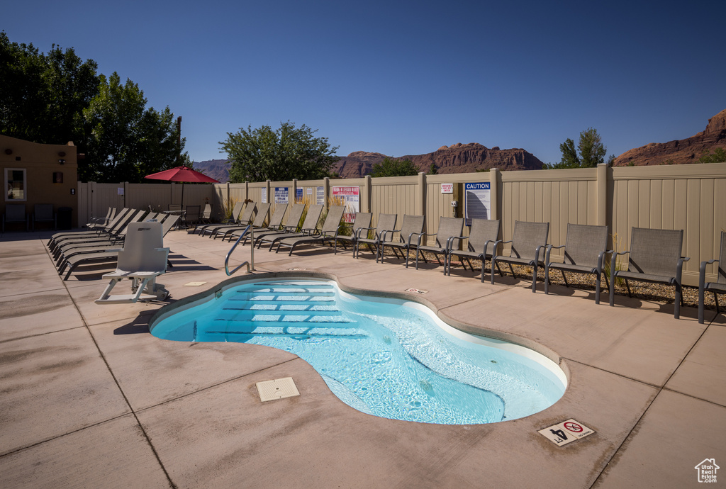 Community pool featuring fence, a mountain view, and a patio