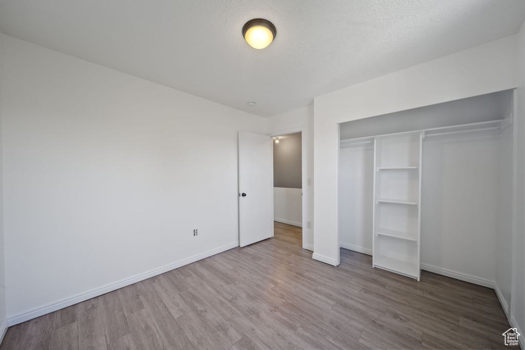Unfurnished bedroom with wood finished floors, a closet, and baseboards