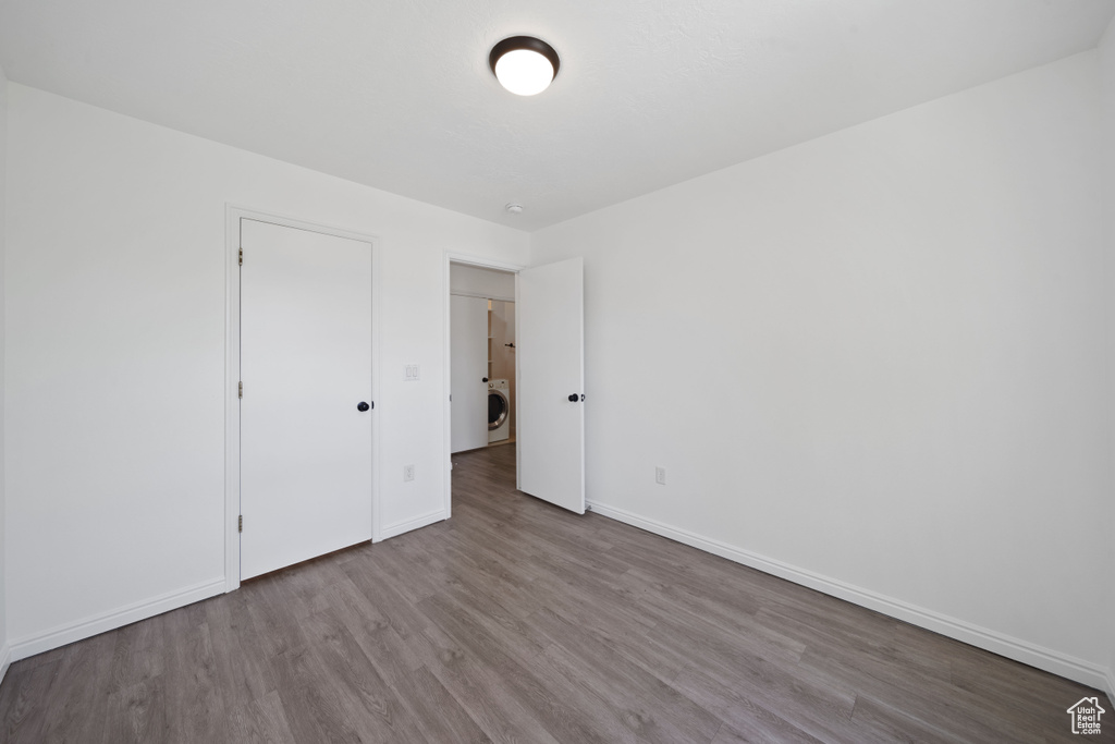 Unfurnished bedroom featuring wood finished floors, baseboards, and washer / clothes dryer