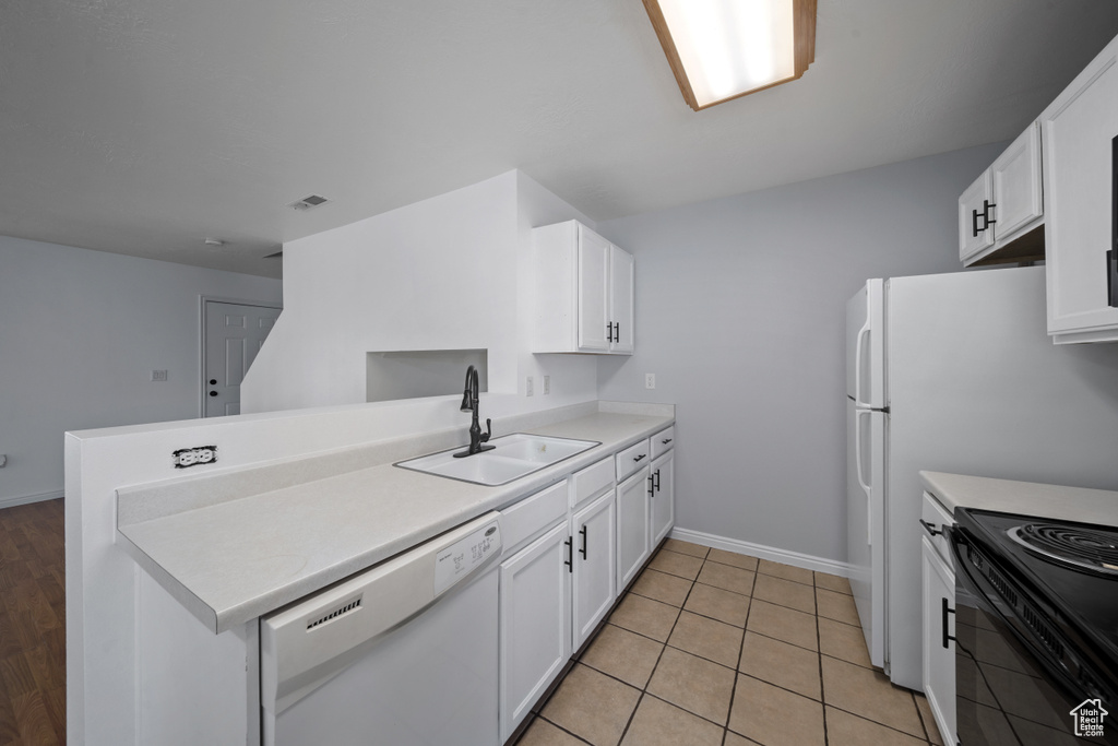 Kitchen with white dishwasher, a sink, a peninsula, and white cabinets