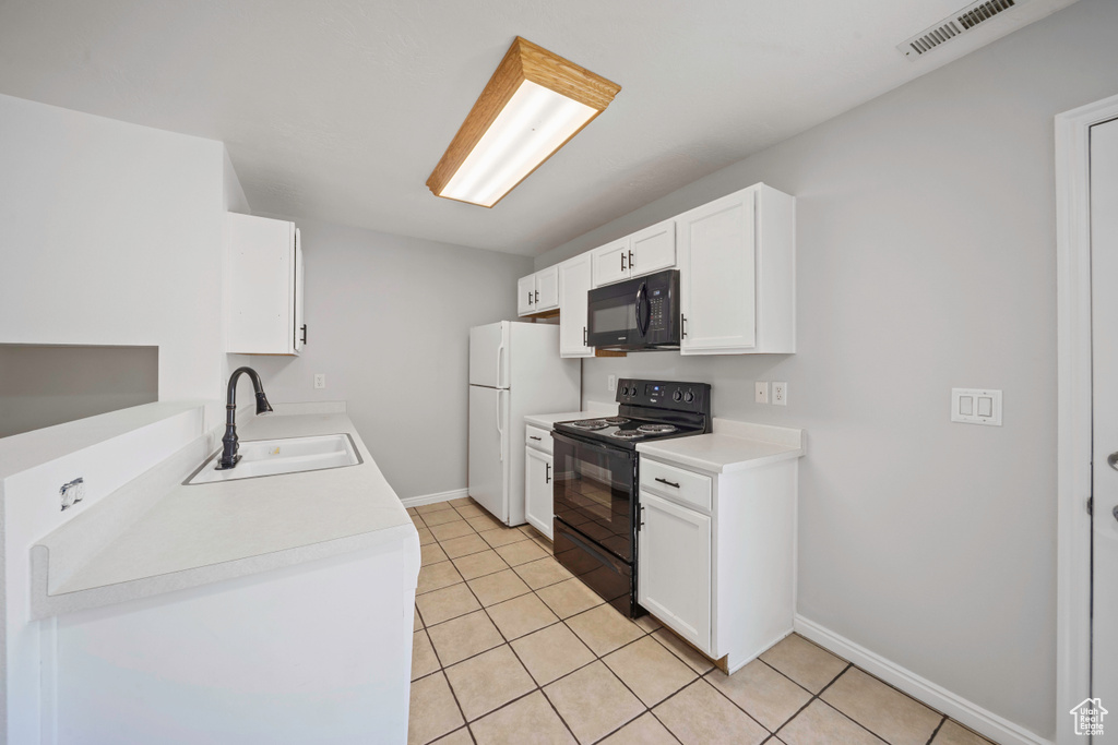 Kitchen with black appliances, a sink, baseboards, light tile patterned floors, and white cabinetry
