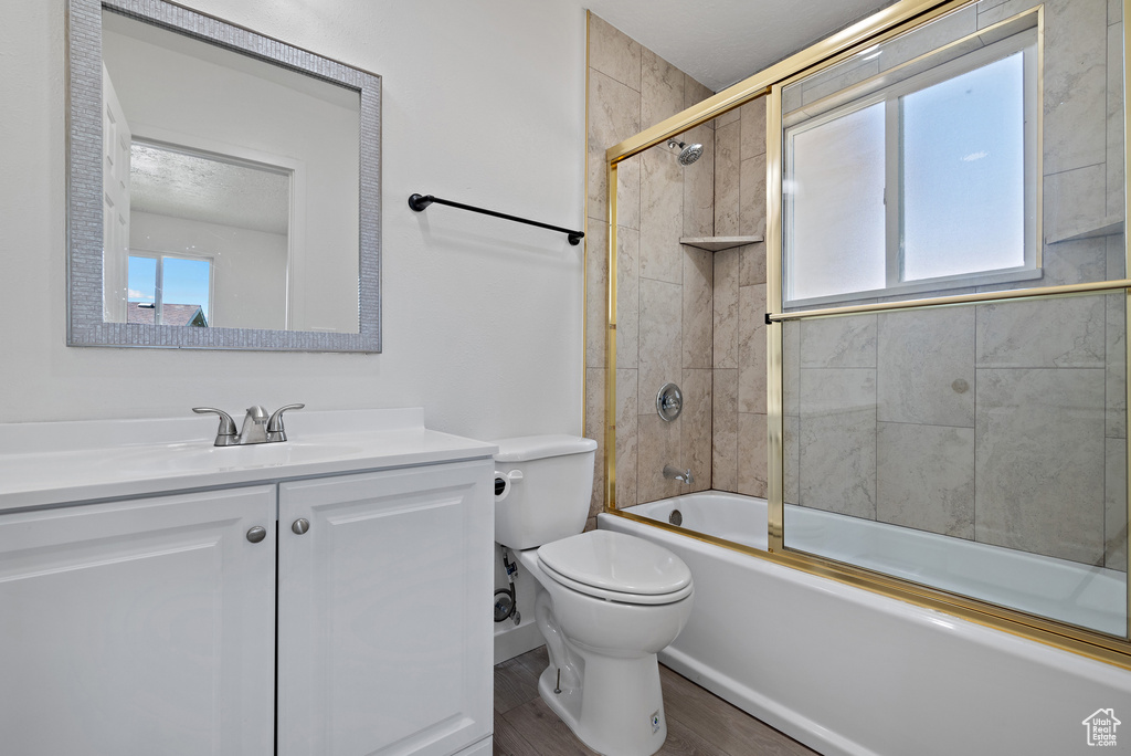 Full bath with plenty of natural light, vanity, toilet, and shower / bath combination with glass door