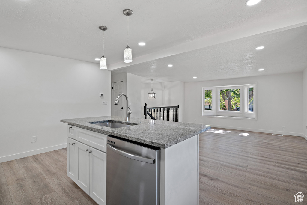 Kitchen with stainless steel dishwasher, a sink, recessed lighting, light wood-type flooring, and open floor plan