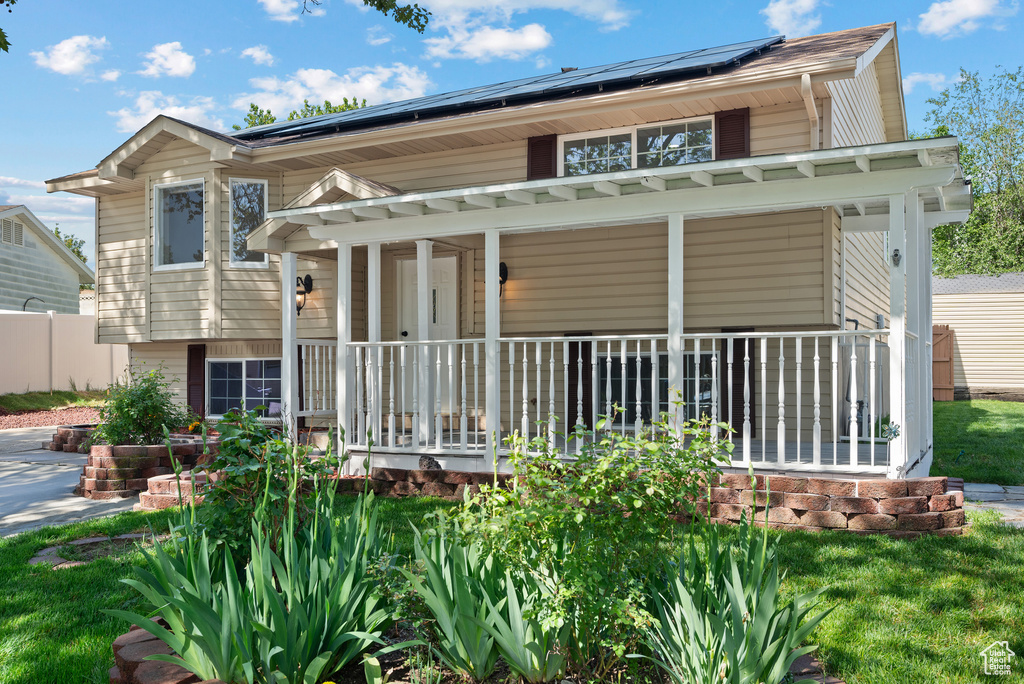 Rear view of property featuring a porch and roof mounted solar panels