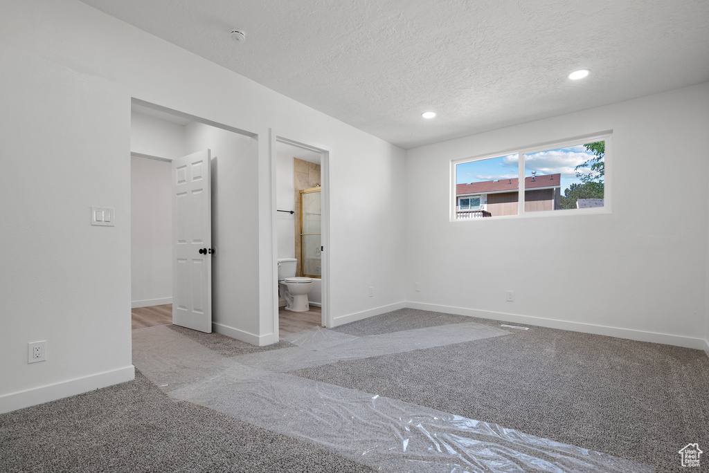 Unfurnished bedroom featuring carpet floors, baseboards, recessed lighting, a textured ceiling, and ensuite bath
