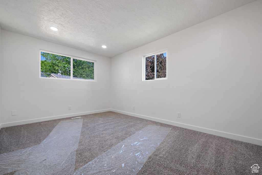 Spare room with carpet, a textured ceiling, baseboards, and recessed lighting