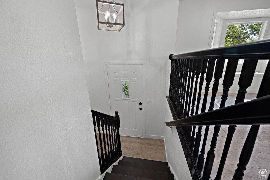 Stairway featuring wood finished floors, baseboards, and a chandelier