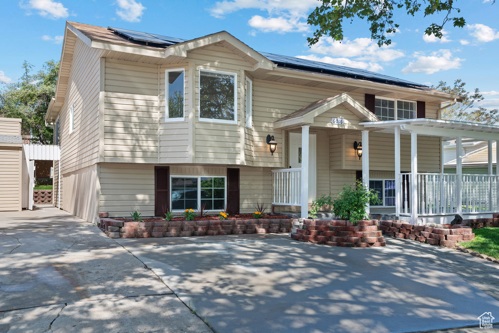 View of front of property with covered porch and roof mounted solar panels