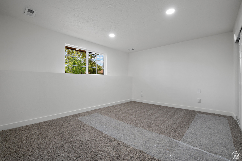 Carpeted empty room with recessed lighting and baseboards