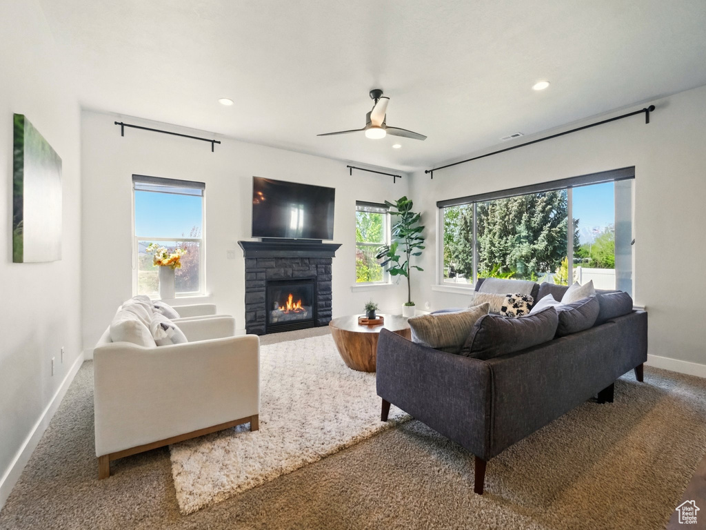 Living room featuring baseboards, recessed lighting, a stone fireplace, ceiling fan, and carpet floors