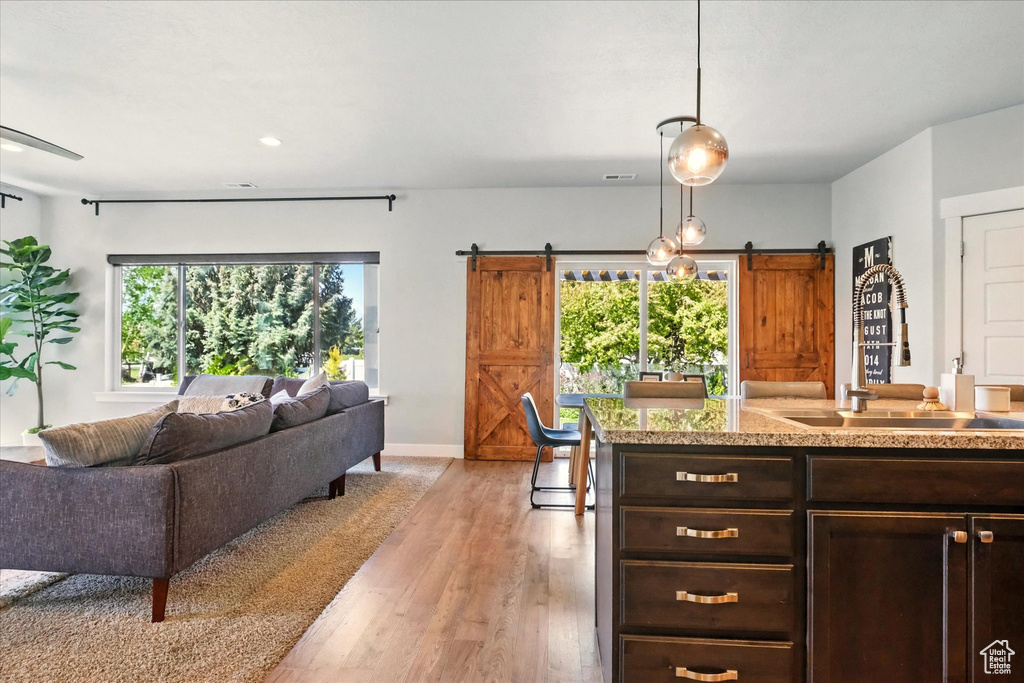 Kitchen with a barn door, a sink, open floor plan, light countertops, and dark brown cabinets