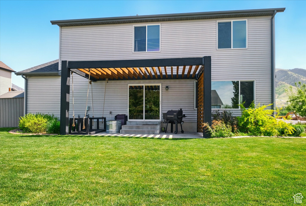 Back of property featuring a patio area, a yard, and a mountain view