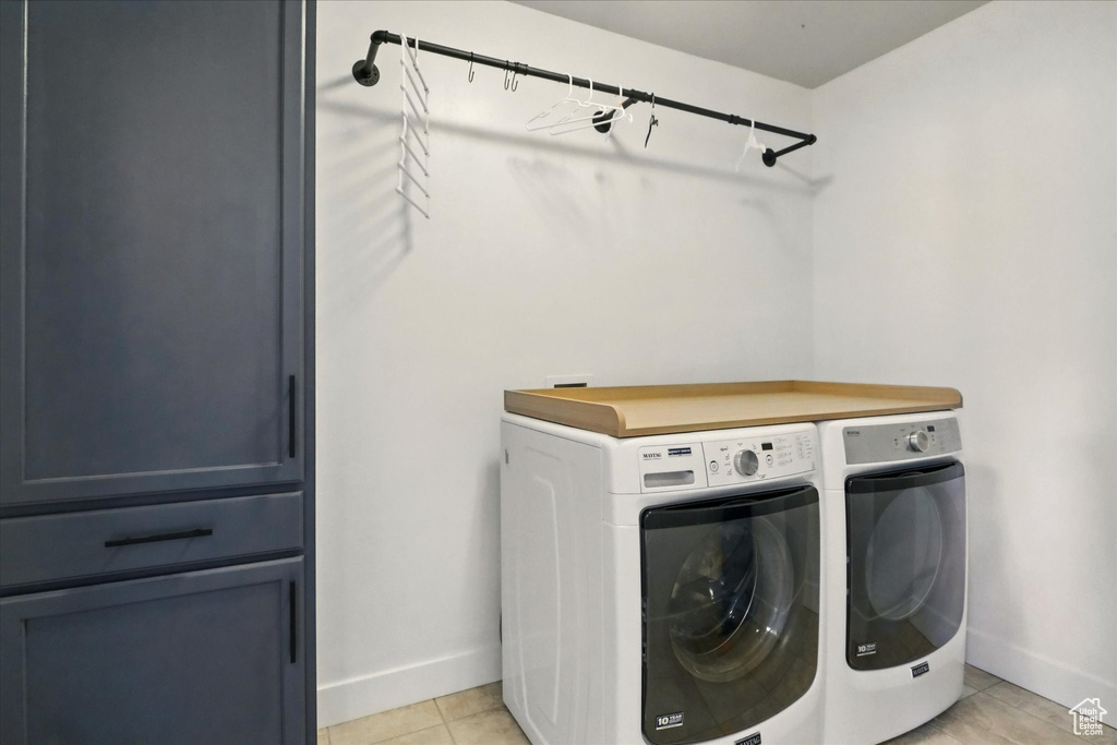 Laundry area featuring washer and dryer, baseboards, and light tile patterned floors