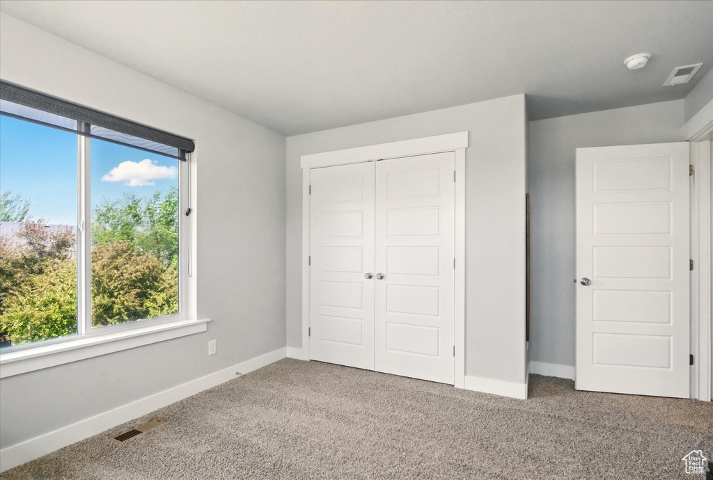 Unfurnished bedroom featuring carpet, a closet, and baseboards