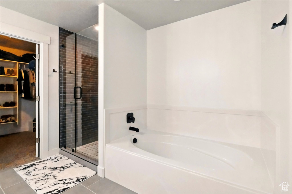 Full bathroom with a stall shower, tile patterned floors, a walk in closet, and a garden tub